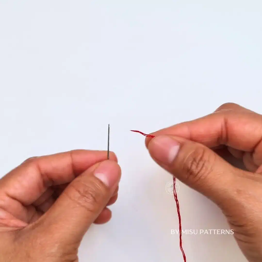 Insert the thread through the eye of the needle and pull it until both ends are uneven.
