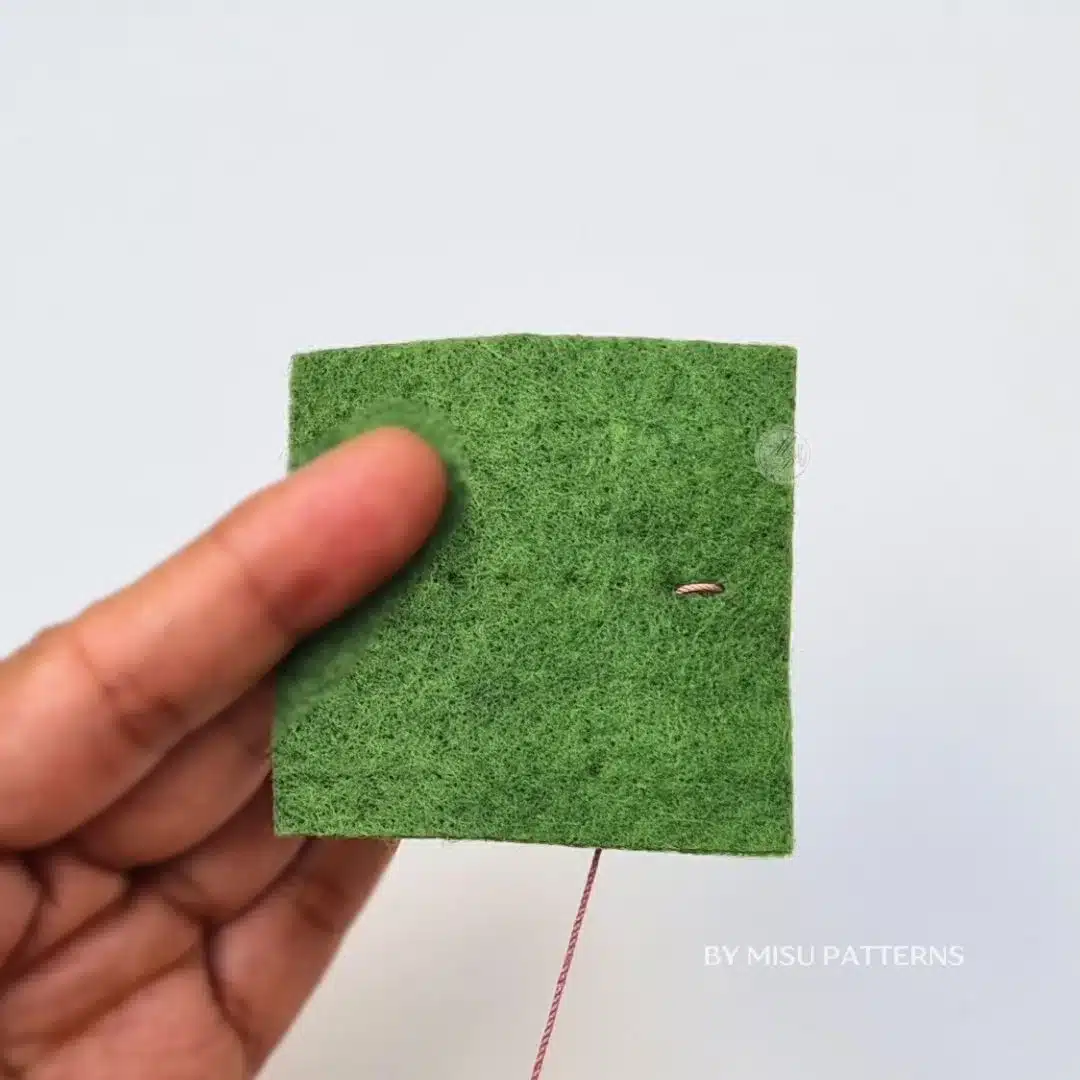Needle inserted a short distance forward into the felt to begin the first stitch.