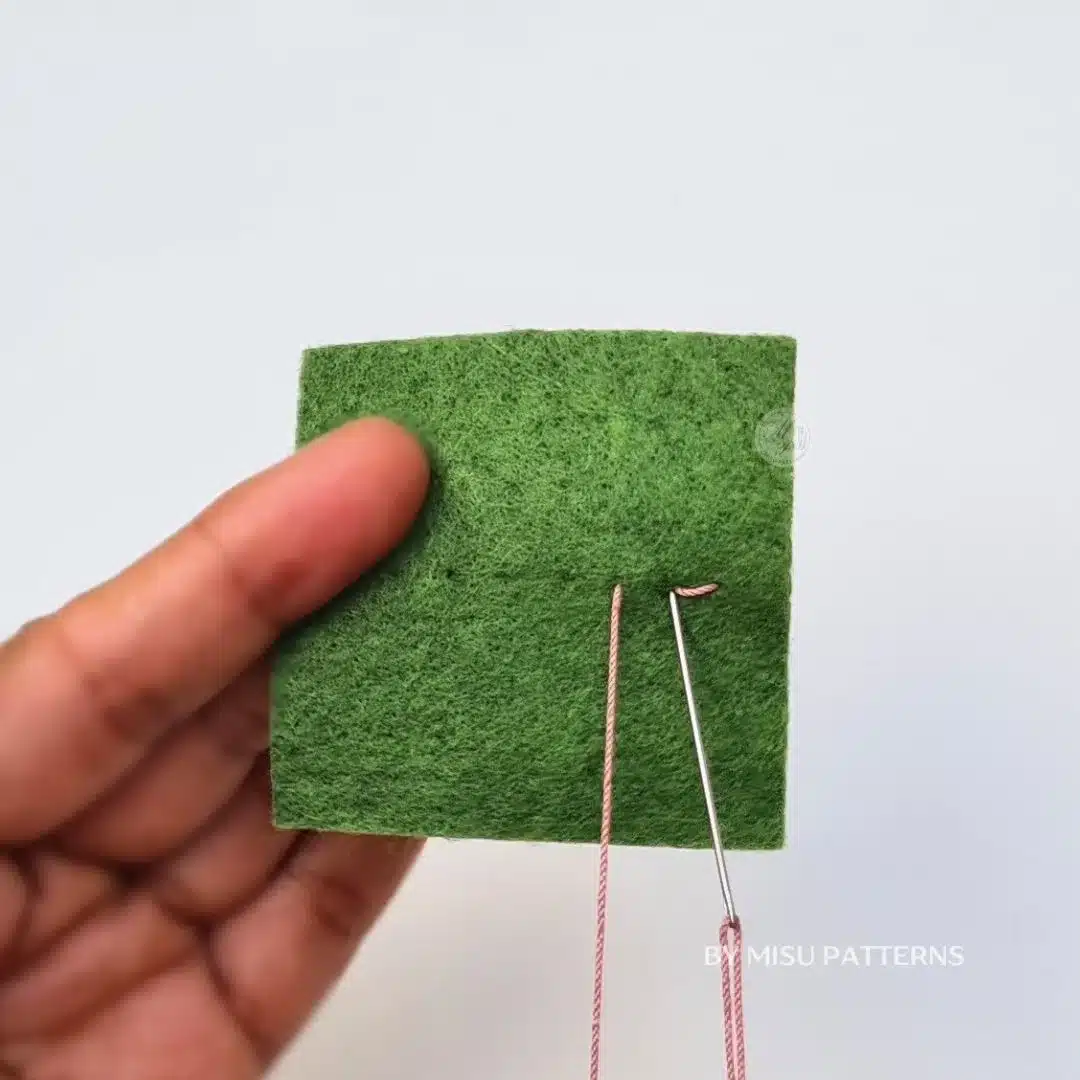 Needle coming back up at the end of the previous stitch, forming the backstitch motion.