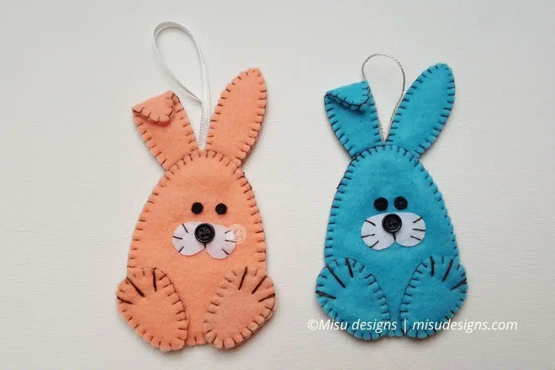 Front view of handmade Easter felt bunny ornaments in melon and light blue