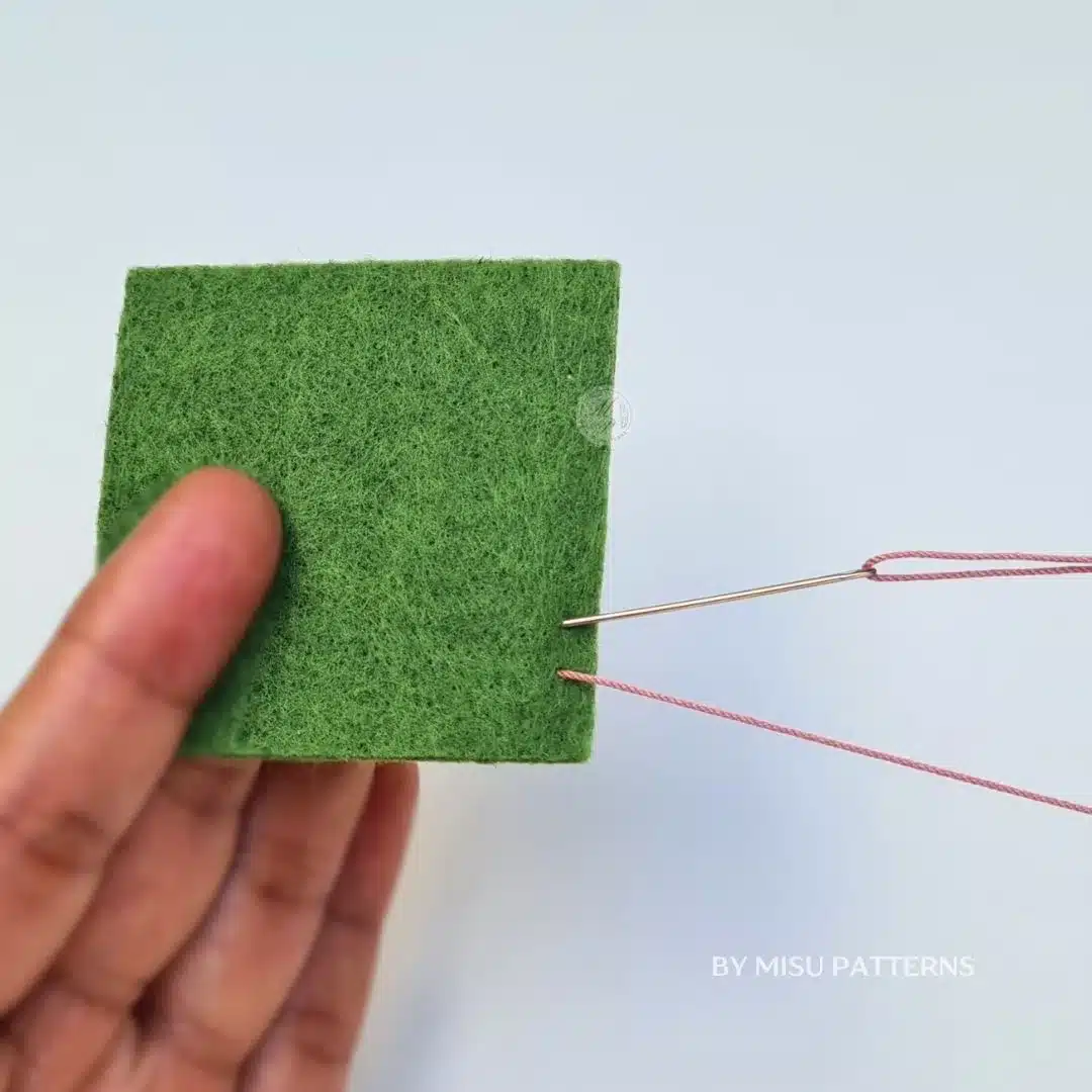 Insert the needle back down into the fabric a short distance from where it came out.