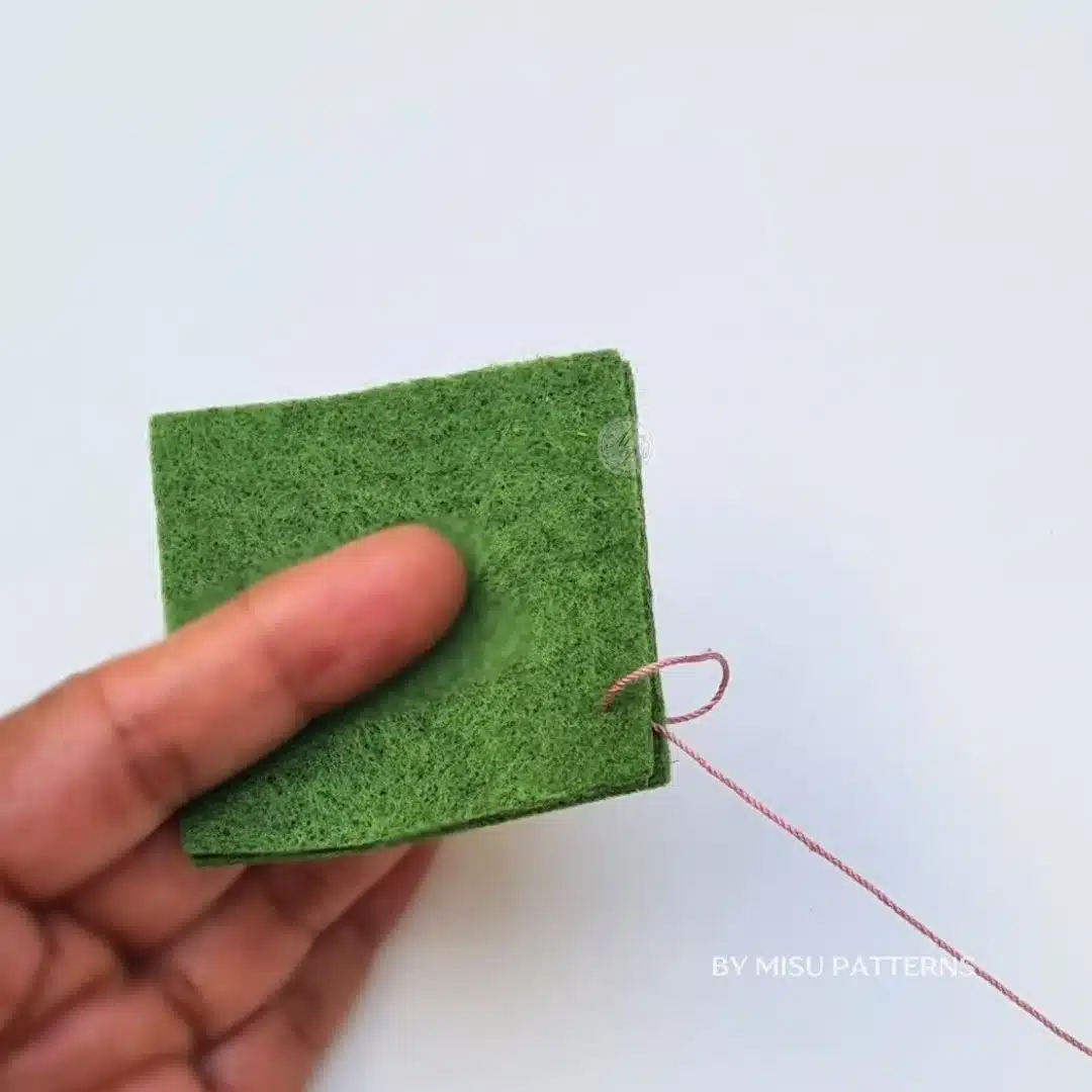 Bringing the needle forward and pulling the thread through the loop to lock the stitch.