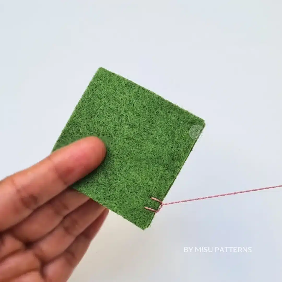 Passing the needle over the thread loop to catch the blanket stitch.