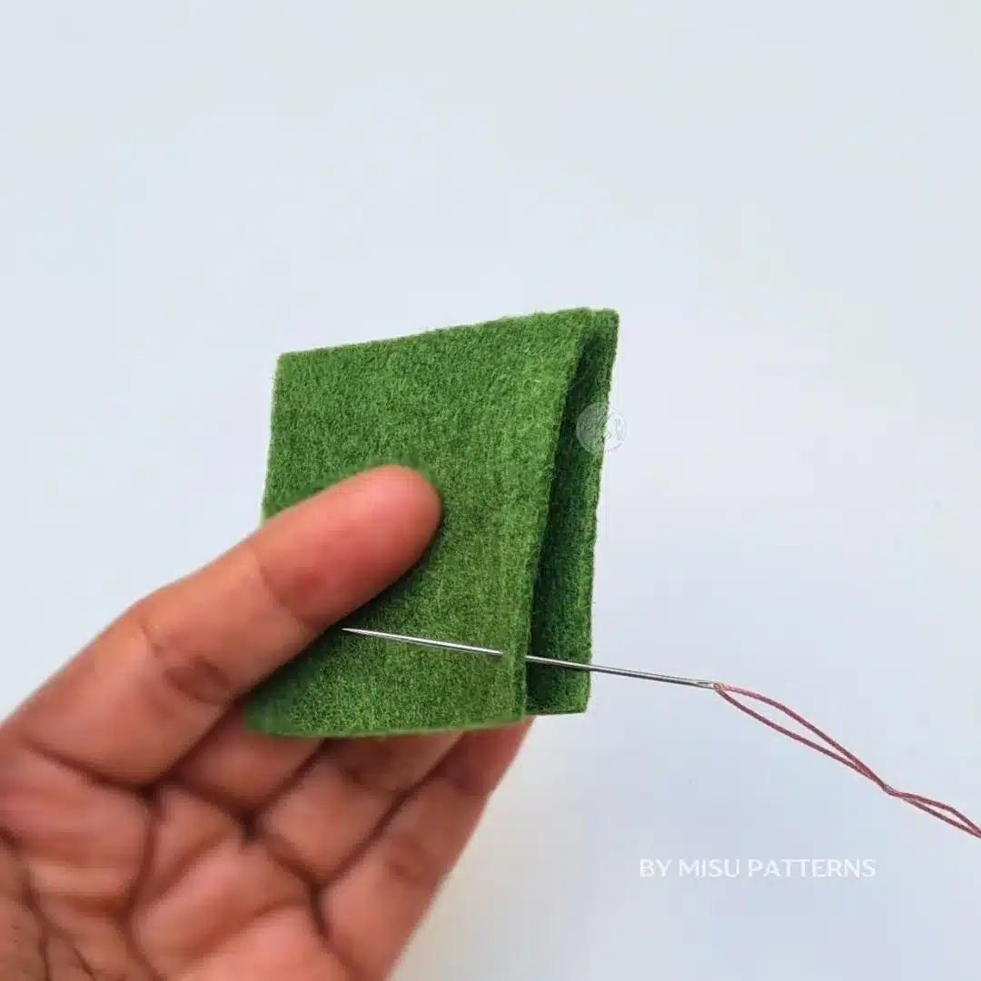 Inserting a needle from the back to the front of the fabric to start a blanket stitch.