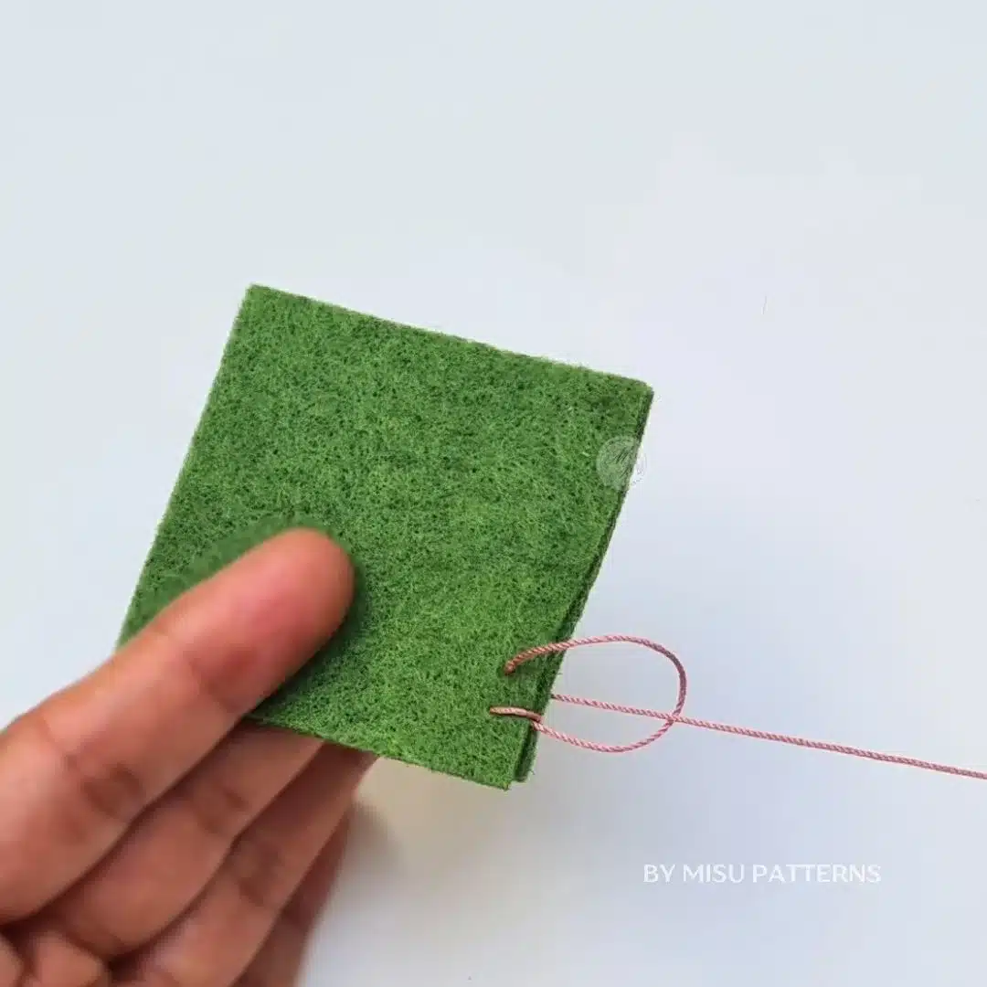 Positioning the sewing needle over the working thread loop to catch the blanket stitch.