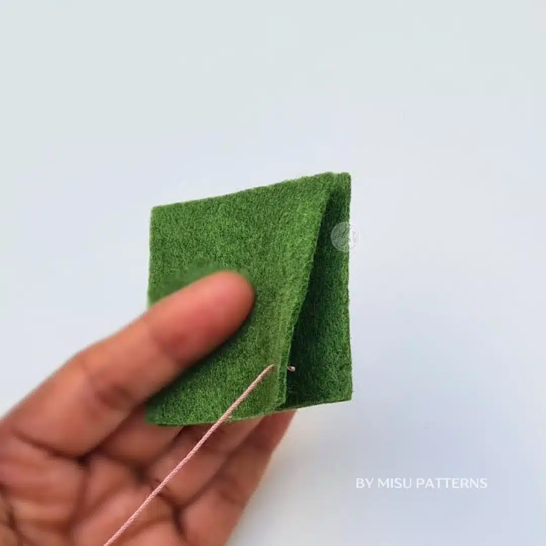Pulling the thread until the knot is hidden on the backside of the fabric to anchor a blanket stitch.