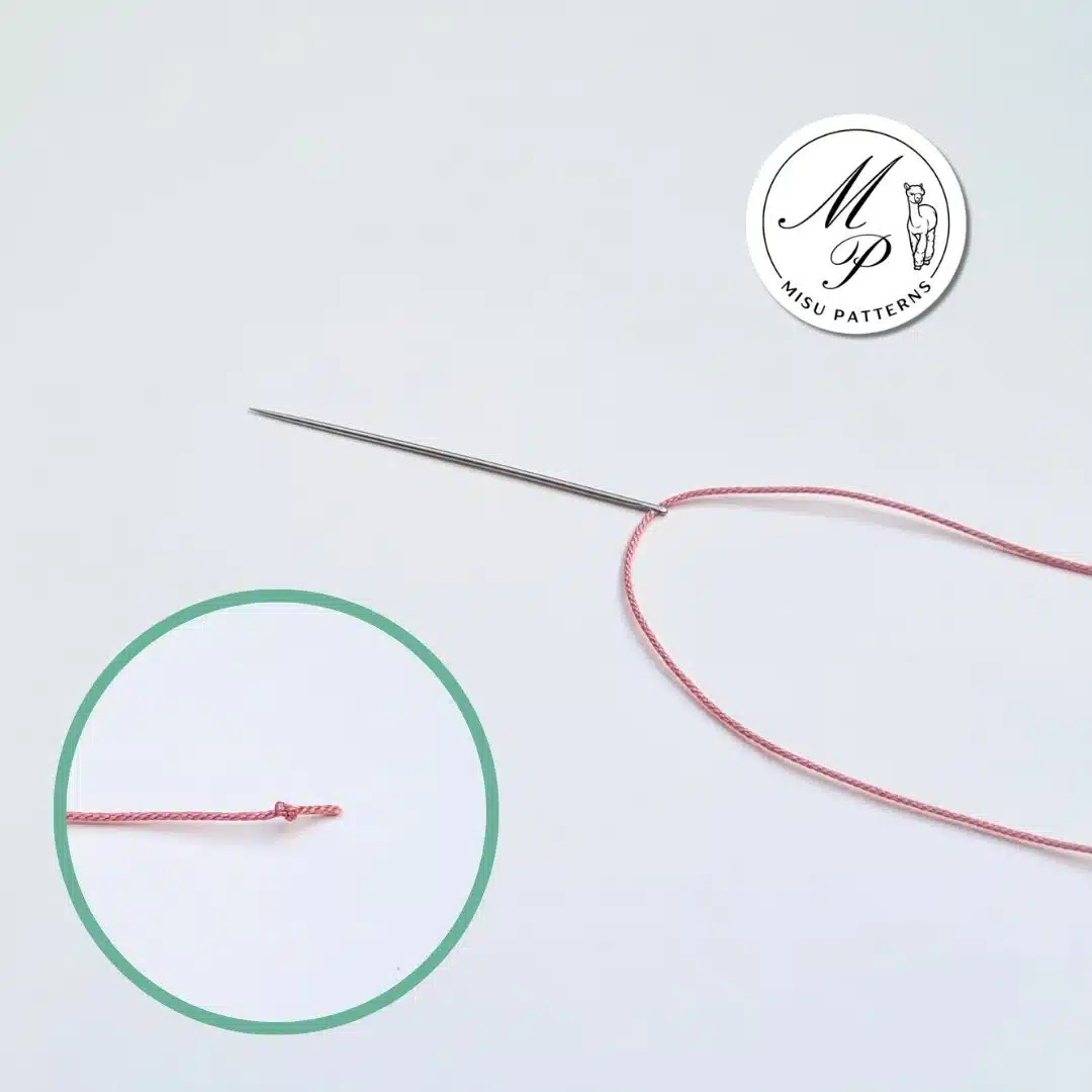 Cut a piece of thread and insert it through the needle. Tie a small knot at one end.
